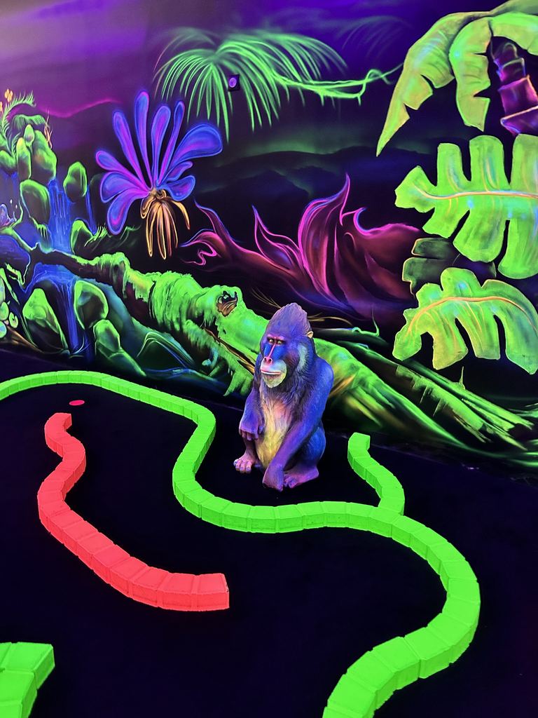 Statue de gorille fluo au milieu des feuilles peintes