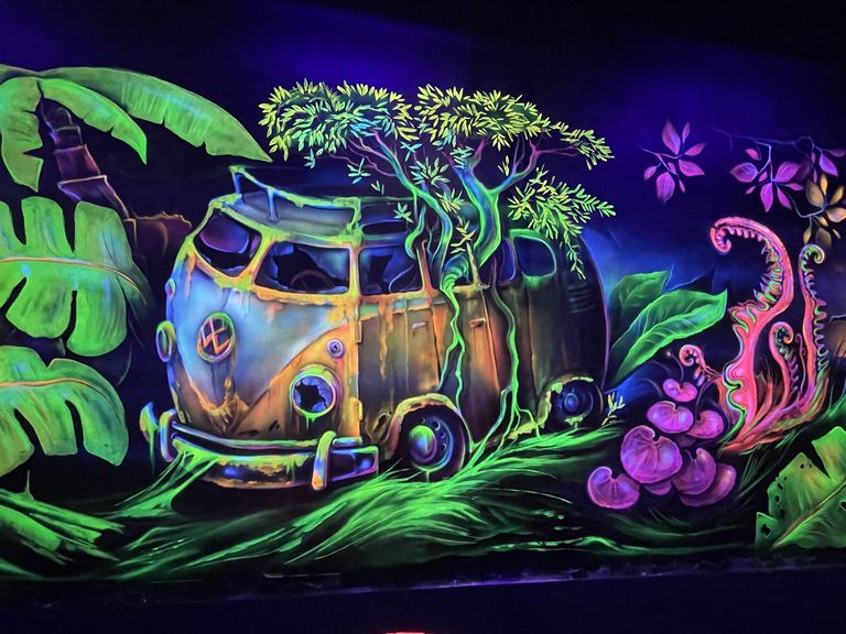 Fresque fluo d'un van Volkswagen envahi par la jungle